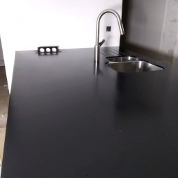 MEBLE XY NORBERT BOGDANOW - Czarny blat kuchenny z metalowym zlewem i baterią w Dąbcze, oświetlenie podszafkowe, nowoczesny design, minimalistyczne wykończenie.