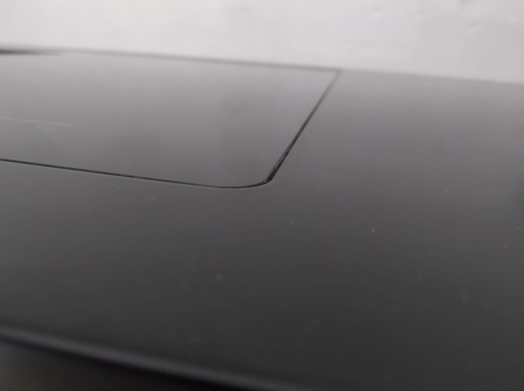 Czarny, gładki blat z subtelnym zaokrągleniem krawędzi i delikatną szczeliną, ukazany z bliska pod kątem, podkreślającym minimalistyczny design.