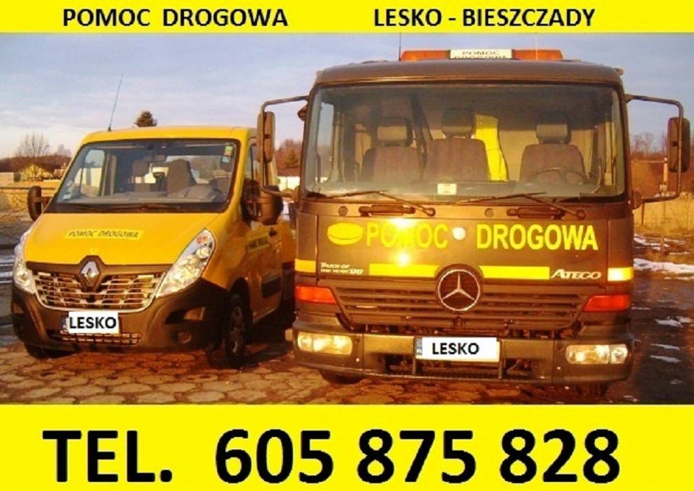 Dwa pojazdy pomocy drogowej: żółty Renault Master i brązowy Mercedes Atego, z napisem 'POMOC DROGOWA' i numerem telefonu, sfotografowane w Lesku.