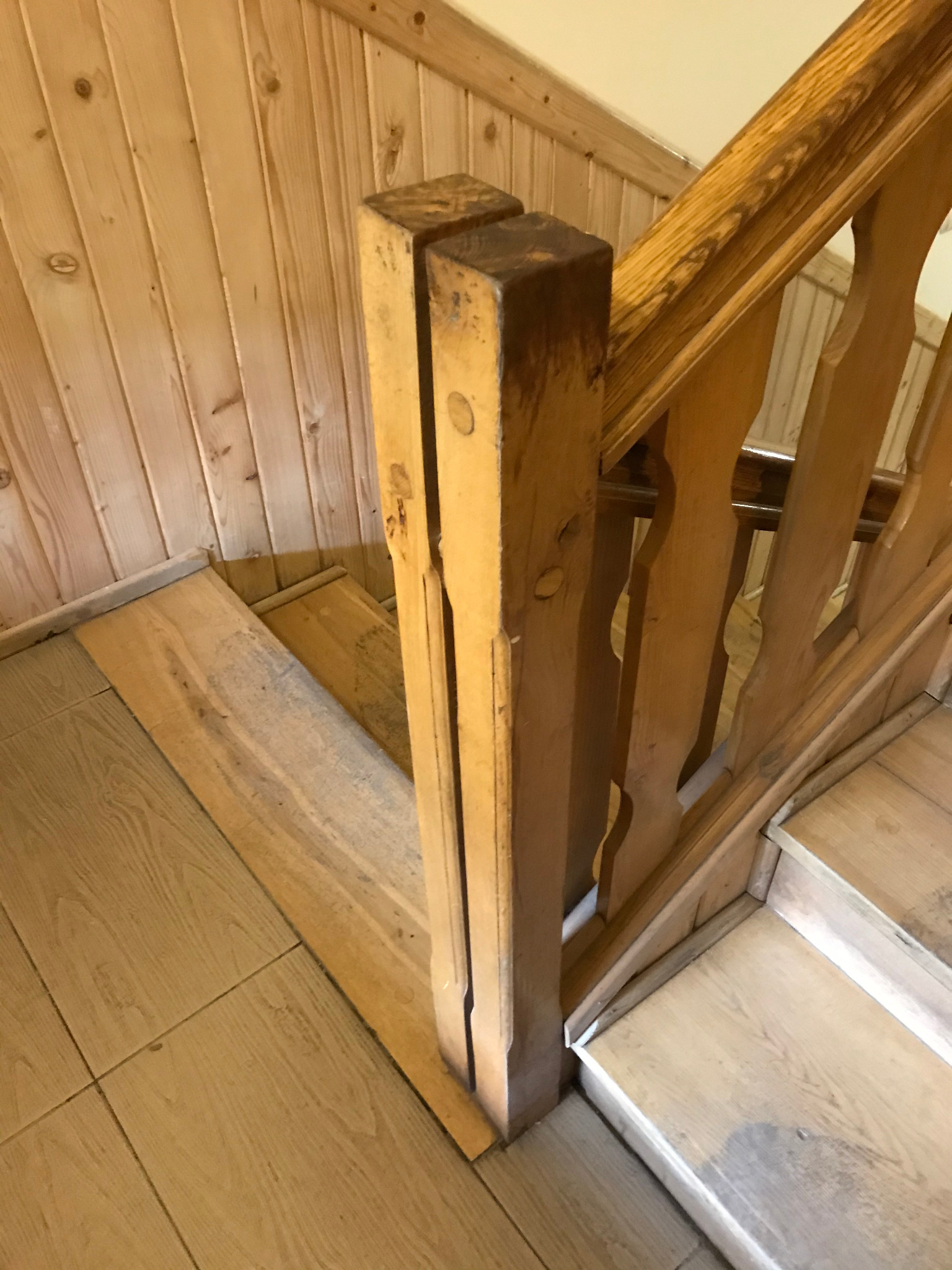 Drewniane schody z balustradą w trakcie cyklinowania, widoczne niedoskonałości na słupku balustrady i desce podstopnicy.