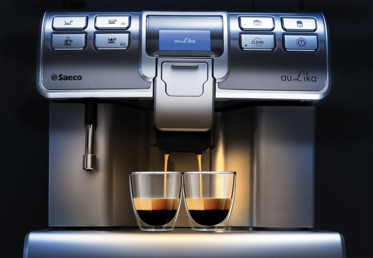 Profesjonalny ekspres Saeco Au-Lika przygotowuje espresso do dwóch szklanych filiżanek, widoczne srebrne przyciski funkcyjne i wyświetlacz.