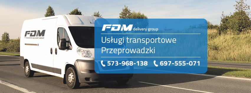 Biały bus FDM Delivery Group z naklejoną reklamą usług transportowych i przeprowadzek, zaparkowany na drodze w słoneczny dzień.