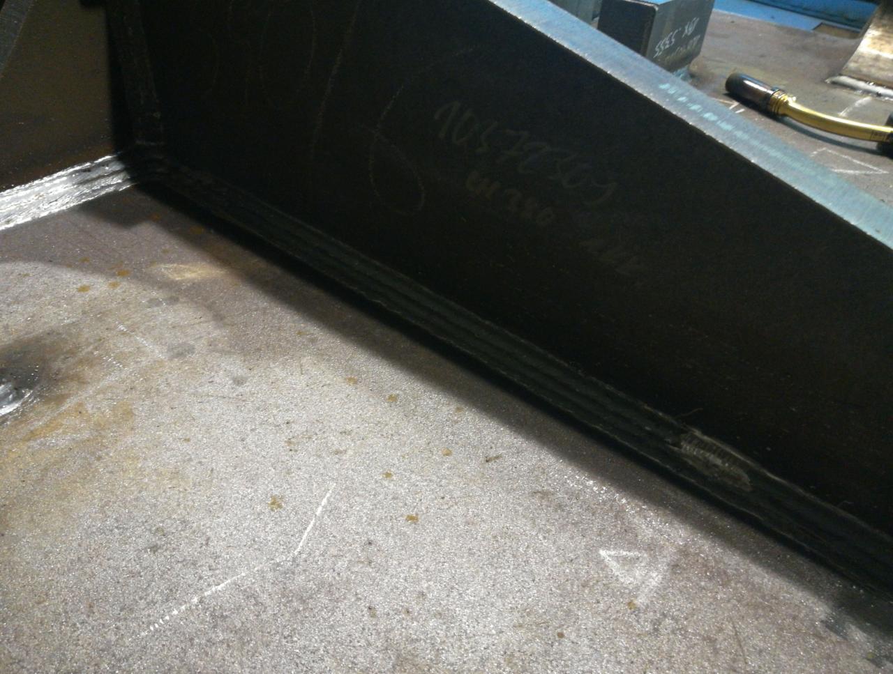 Metalowa konstrukcja z widocznymi, świeżo wykonanymi spawami łączącymi elementy; na powierzchni konstrukcji widoczne napisy wykonane kredą.