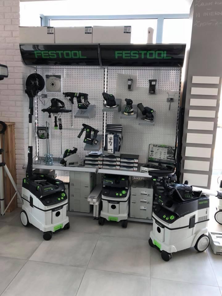 Ekspozycja narzędzi i odkurzaczy przemysłowych marki Festool na tle perforowanej ściany w sklepie.