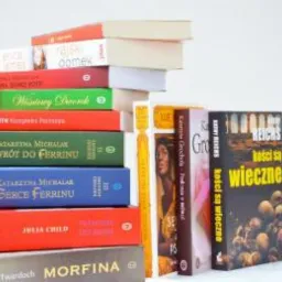 Stos książek o różnej grubości i kolorach okładek, ułożonych schodkowo na białym tle, z widocznymi tytułami i nazwiskami autorów.