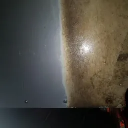 Fragment powierzchni przed i po czyszczeniu, widoczne silne zabrudzenia i efekt działania środka czyszczącego.