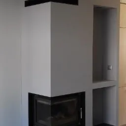 Szary narożny kominek z czarnymi akcentami, wbudowany w ścianę z półkami, widok z boku, nowoczesny design.