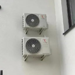 Dwa klimatyzatory marki Rotenso zamontowane na białej elewacji budynku, widoczne wsporniki montażowe i fragment rusztowania w dolnej części kadru.