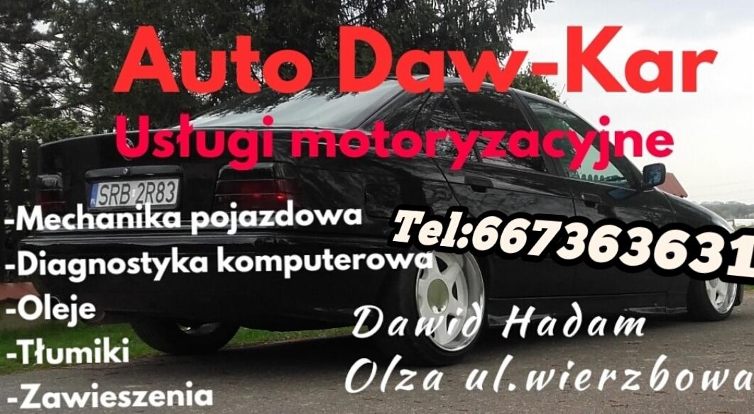 Czarny samochód z napisem 'Auto Daw-Kar Usługi motoryzacyjne' oraz listą usług mechanicznych i numerem telefonu, widoczne tablice rejestracyjne SRB 2R83, reklama warsztatu Dawid Hadam Olza ul.