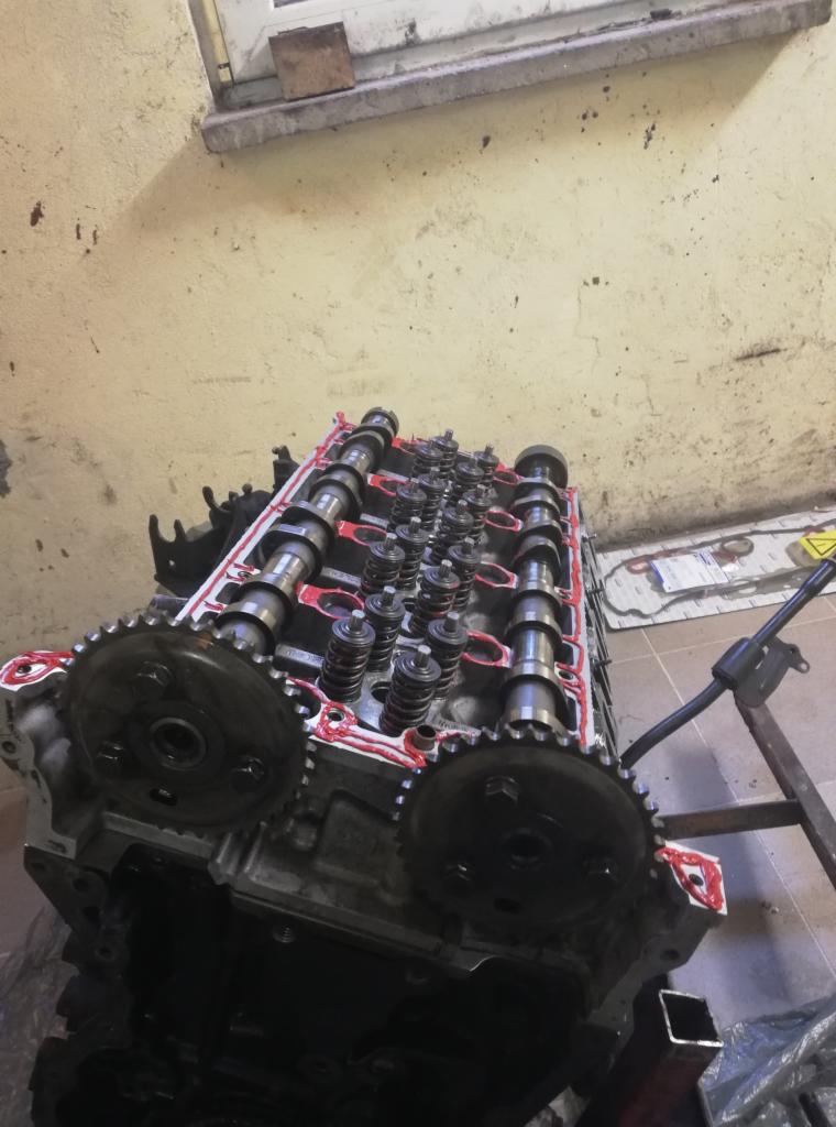 Zdemontowana głowica silnika samochodowego z wałkami rozrządu i sprężynami zaworowymi, przygotowana do ponownego montażu, z widocznymi śladami silikonu uszczelniającego.