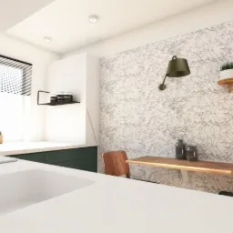 Nowoczesna kuchnia z białym blatem, zielonymi szafkami i tapetą w delikatny wz&oacute;r liści, oświetlona zieloną lampą ścienną i naturalnym światłem z okna z żaluzjami.