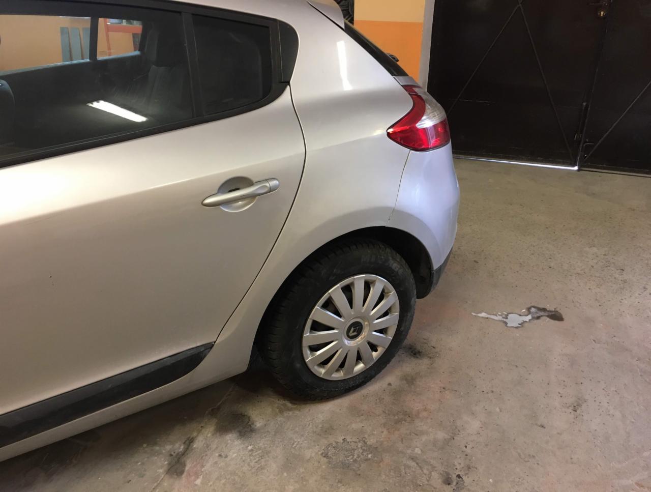 Srebrny samochód, widok z tyłu, zarysowany próg, plama na betonowej podłodze garażu.