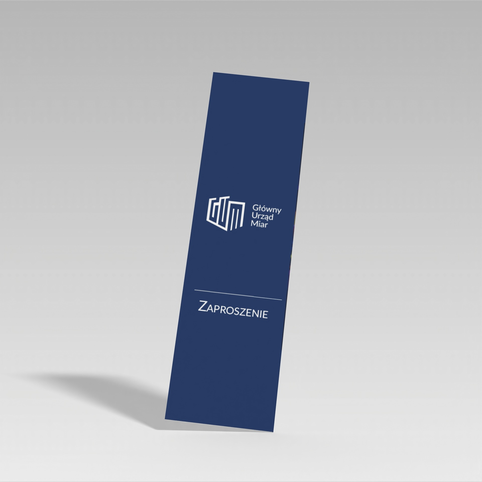 Eleganckie, granatowe zaproszenie od Głównego Urzędu Miar w Warszawie, z minimalistycznym logo i napisem 'Zaproszenie', ustawione pod kątem na jasnym tle.