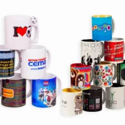 Kolekcja różnorodnych, białych ceramicznych kubków z nadrukami, ułożonych w dwie piramidy na białym tle, prezentujących przykładowe wzory i grafiki.