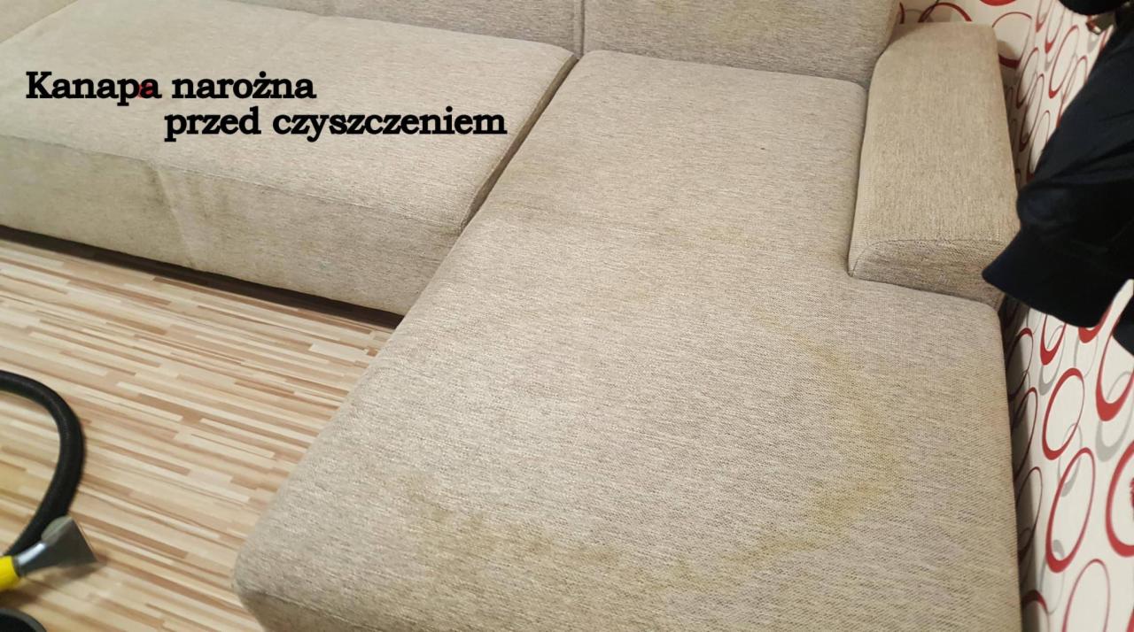 Beżowa kanapa narożna z widocznymi plamami, przygotowana do czyszczenia w Działdowie. W tle widoczna rura odkurzacza piorącego i wzorzysta tapeta.