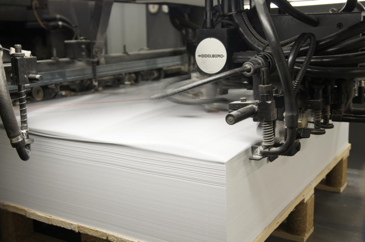 Stos arkuszy papieru w maszynie drukarskiej Heidelberg podczas procesu drukowania.