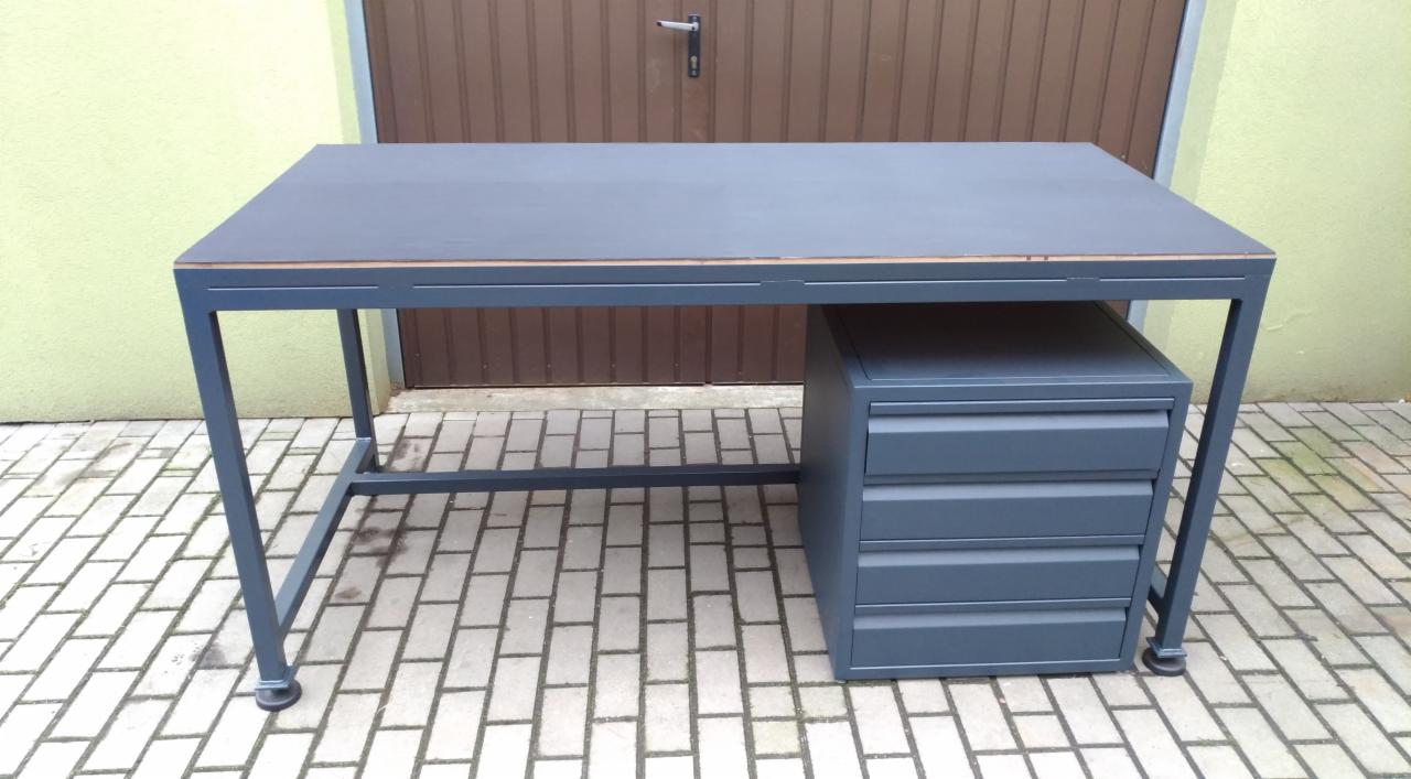 Metalowy stół warsztatowy z szufladami w kolorze grafitowym, na zewnątrz, z widoczną konstrukcją spawaną i drewnianym blatem.