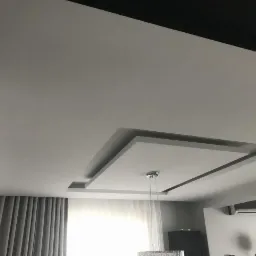 Nowoczesny sufit podwieszany z dekoracyjnym wgłębieniem w kształcie kwadratu, oświetlony wiszącą lampą, widok z dołu.