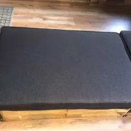 Szare, tapicerowane poduszki siedziskowe na meblach z palet, widoczne sznurki mocujące.