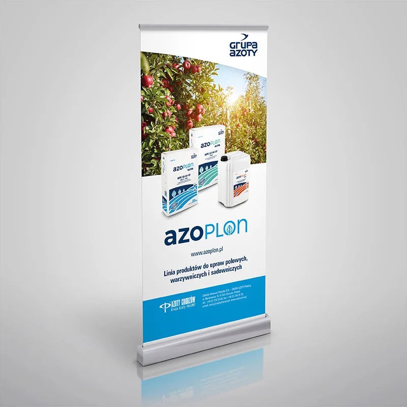 Roll-up reklamowy Grupy Azoty z produktami AzoPlon na tle sadu jabłoniowego, prezentacja linii produktów dla upraw polowych, warzywniczych i sadowniczych.