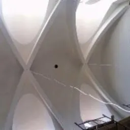 Białe sklepienie krzyżowe w trakcie renowacji, widoczne ślady napraw i rusztowanie w tle.