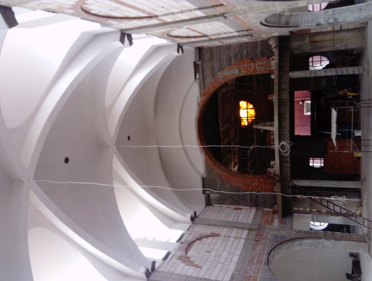 Wnętrze kościoła w Ostrowcu Świętokrzyskim w trakcie renowacji, widoczne sklepienie z tynkami gipsowymi i fragmenty ceglanej konstrukcji okiennej.