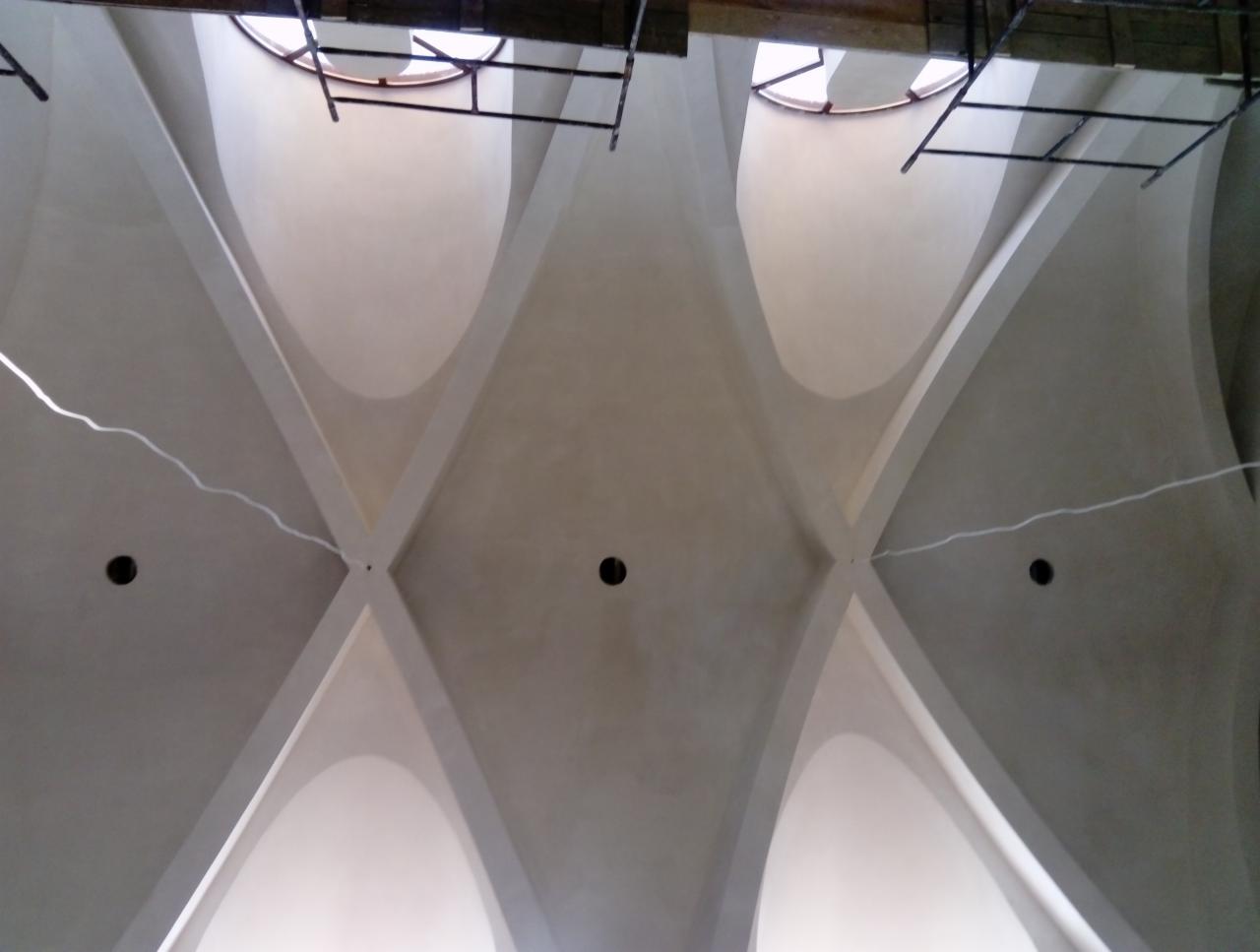 Wnętrze z odnowionym sklepieniem krzyżowym, widoczne otwory na oświetlenie i fragment rusztowania.