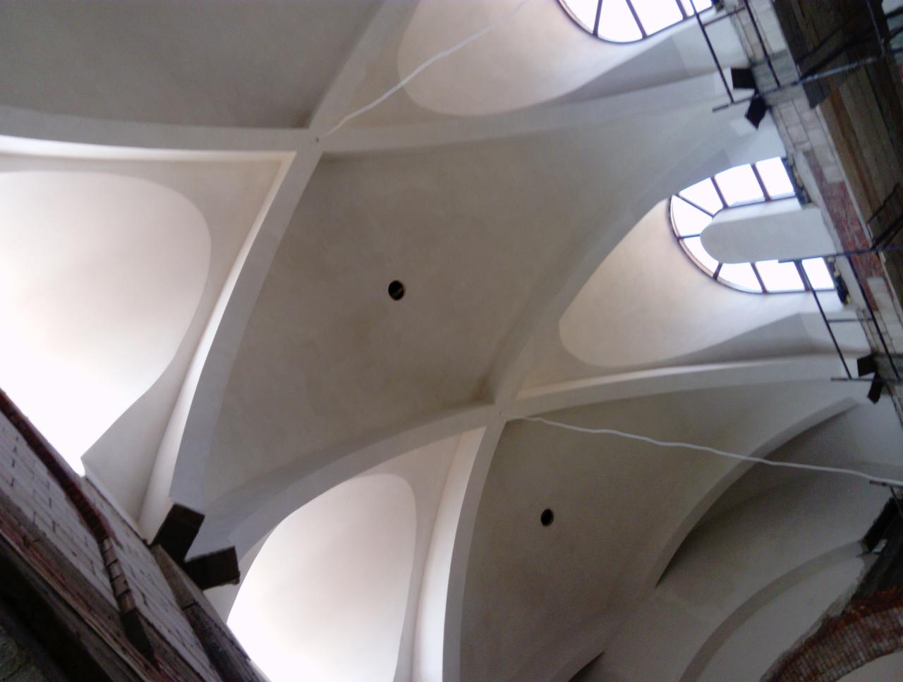 Kopuła sufitowa z oknami dachowymi w trakcie remontu, widoczne rusztowania i fragmenty ceglanego muru.