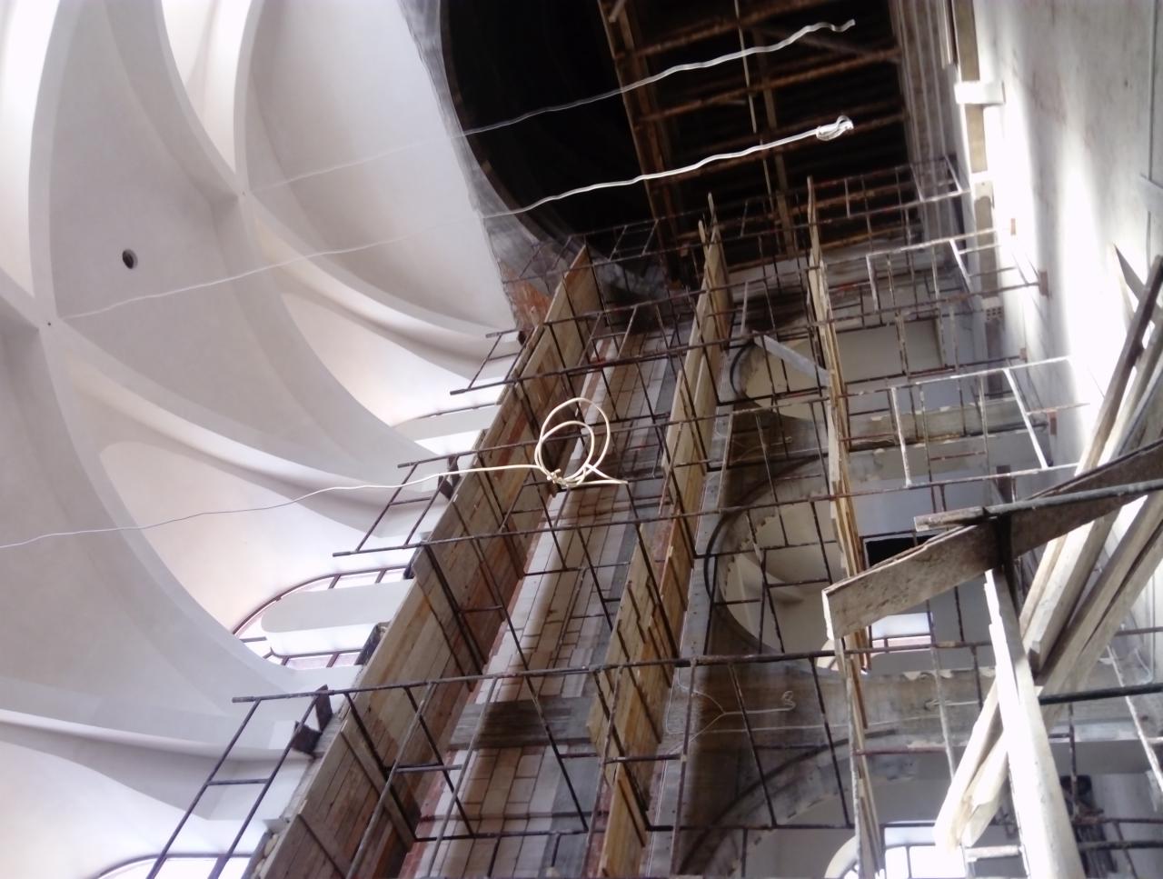 Wnętrze w trakcie prac wykończeniowych z widocznym rusztowaniem i fragmentem dekoracyjnego sufitu.