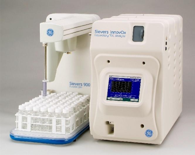 Automatyczny system poboru próbek i analizator TOC, Sievers InnovOx i Sievers 900, z widocznymi probówkami na podstawce i ekranem z wykresem.