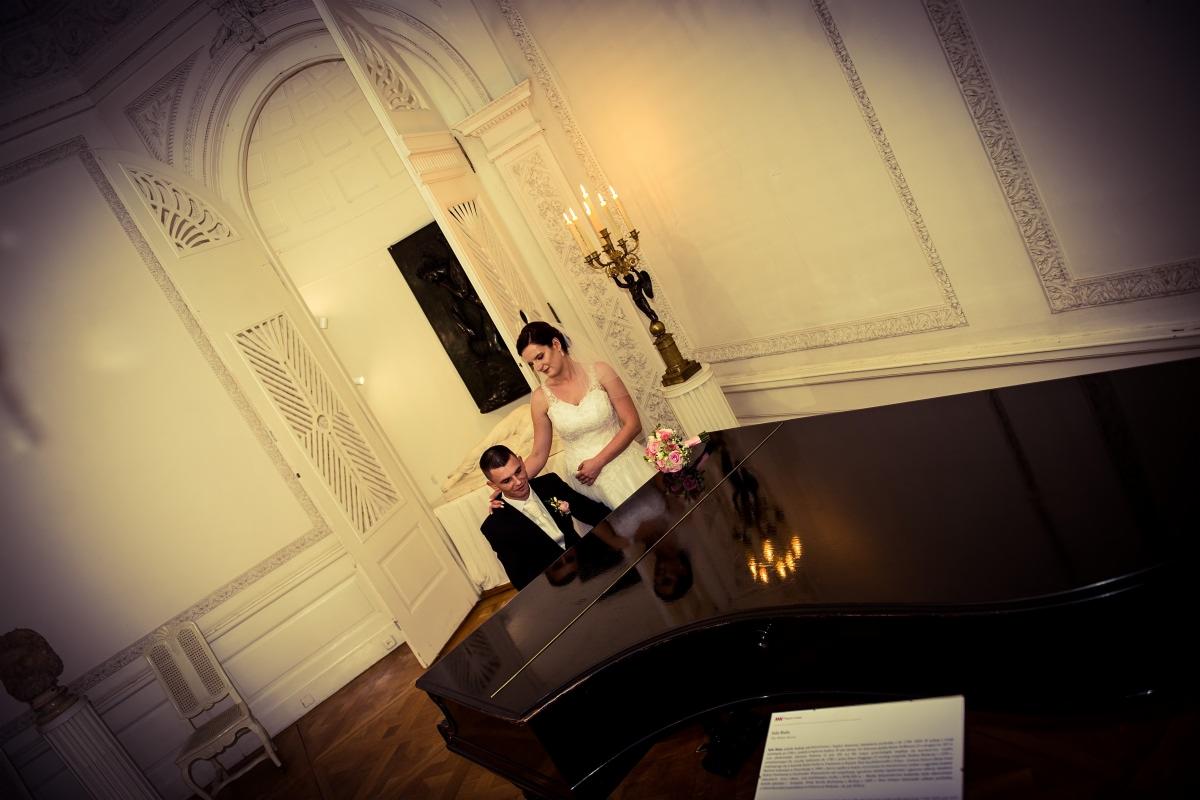 Para młoda w eleganckim wnętrzu z pianinem, świecznikiem i sztukateriami, ujęcie z góry.