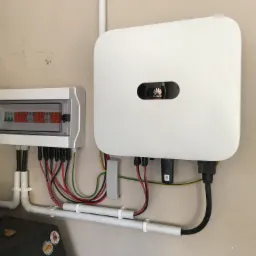 Rozdzielnica elektryczna i inwerter Huawei zamontowane na ścianie, widoczne przewody w peszlach i listwach mocujących.