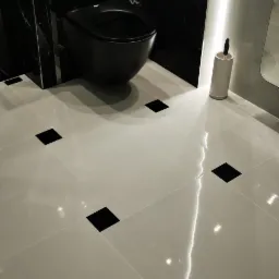 Nowoczesna łazienka z czarną armaturą i białymi płytkami podłogowymi z czarnymi wstawkami, oświetlenie LED, czarne marmurowe ściany.