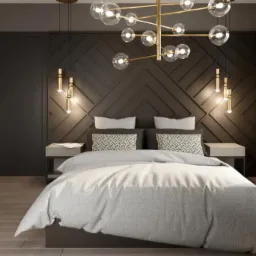 Nowoczesna sypialnia z łóżkiem typu king-size, geometryczną ścianą za wezgłowiem, złotą lampą wiszącą z przezroczystymi kulami i drewnianą podłogą.
