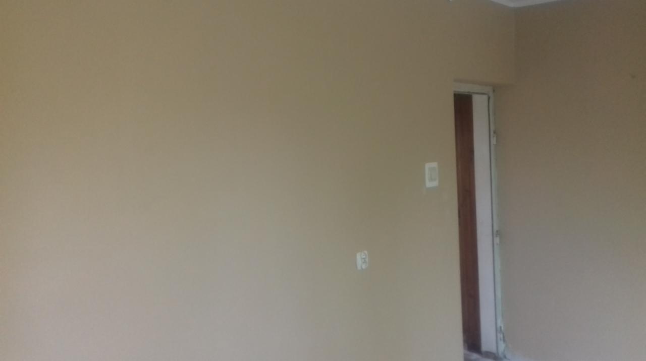 Świeżo pomalowane wnętrze z widocznymi gniazdkami elektrycznymi i fragmentem ościeżnicy drzwiowej w nowym, jednolitym odcieniu beżu.