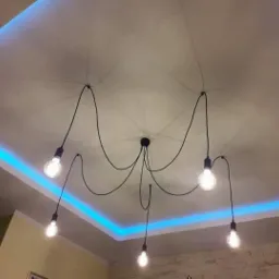 Nowoczesna lampa wisząca z pięcioma żarówkami Edison na tle sufitu z podświetleniem LED w kolorze niebieskim.