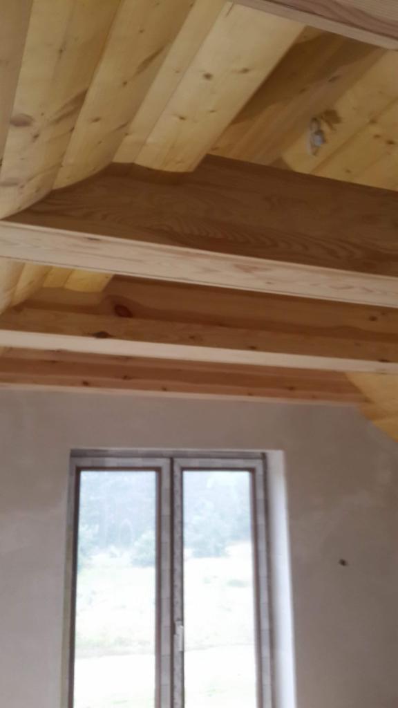 Wnętrze domu w trakcie wykańczania: drewniana podbitka dachowa z widocznym oknem.