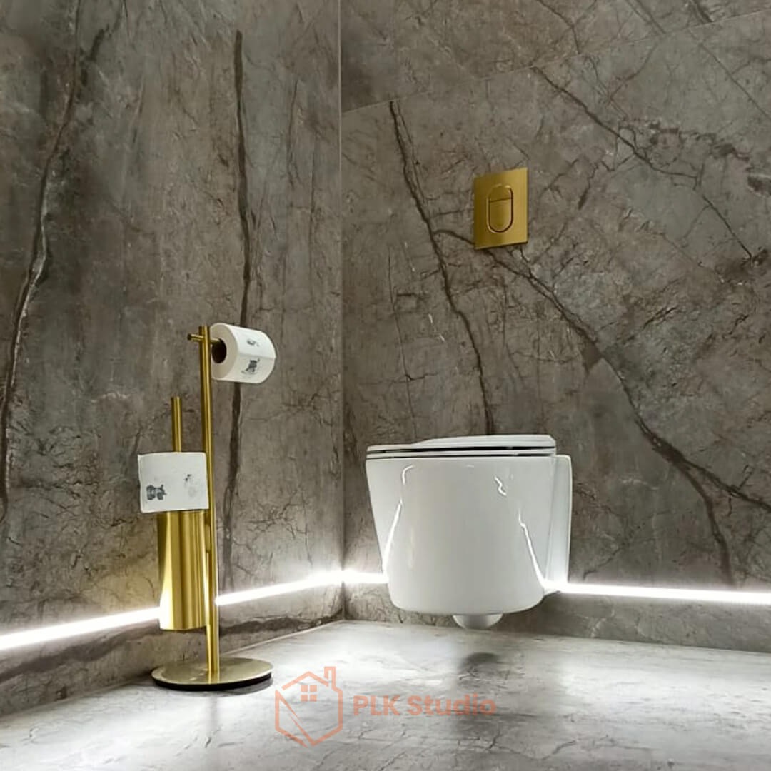 Nowoczesna łazienka z marmurowymi ścianami, podwieszaną toaletą i złotym uchwytem na papier toaletowy. Podświetlenie LED na podłodze dodaje elegancji.