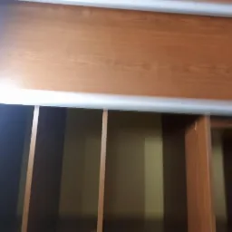 Wnętrze szafy wnękowej z przesuwnymi drzwiami z okleiny drewnopodobnej, widoczne półki i pionowe przegrody.