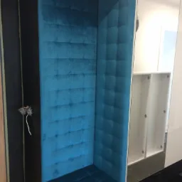 Narożnik tapicerowany turkusowym welurem z pikowaniem w Oleśnicy, wbudowany w zabudowę meblową z widocznym gniazdkiem elektrycznym po lewej stronie.