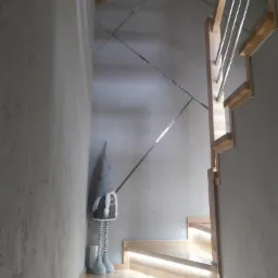 Nowoczesne schody drewniane z podświetleniem LED, dekorowane metalowymi listwami i pluszowym skrzatem w szarościach.