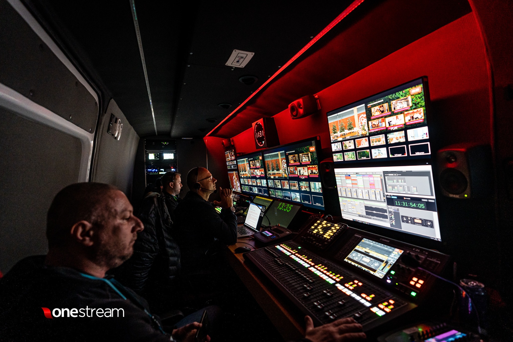 Wnętrze wozu transmisyjnego: operatorzy pracują przy mikserze wizyjnym i monitorach prezentujących podgląd z kamer podczas transmisji na żywo.