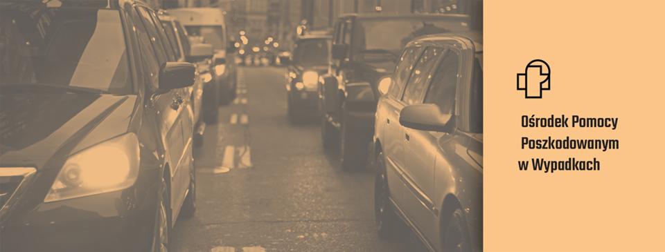 Korek uliczny z widocznymi samochodami i światłami w oddali, obok logo i napis 'Ośrodek Pomocy Poszkodowanym w Wypadkach' na beżowym tle.