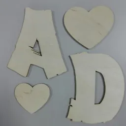 Drewniane litery A i D oraz dwa serca z jasnego drewna na szarym tle, prawdopodobnie elementy dekoracyjne lub do rękodzieła.