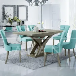Jadalnia w jasnych barwach: stół z drewnianym blatem i nogami w kształcie litery X, otoczony sześcioma turkusowymi krzesłami tapicerowanymi z ozdobnymi nitami, na tle białych ścian i błyszczącej...