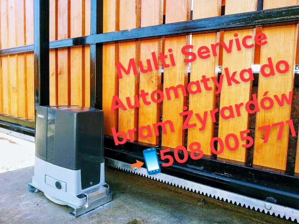 Szary napęd bramy przesuwnej z widoczną listwą zębatą, zamontowany przy drewnianej bramie. Na zdjęciu widoczny napis reklamowy i numer telefonu.