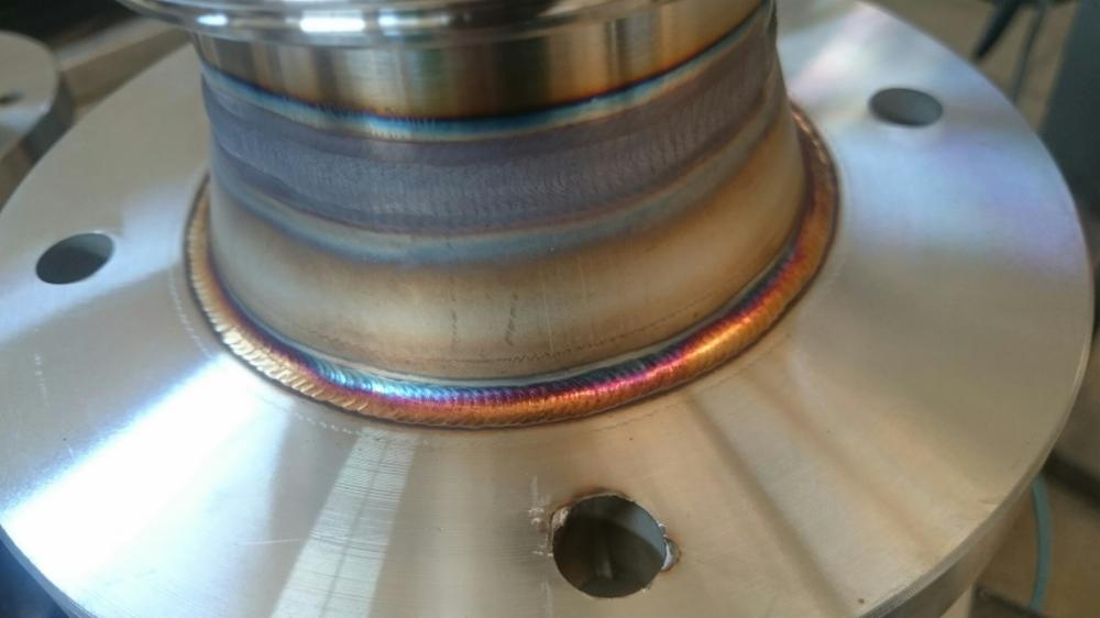 Spoina obwodowa na elemencie metalowym, widoczne charakterystyczne przebarwienia termiczne, otwór w podstawie elementu.