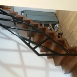 Schody drewniane z nowoczesną, geometryczną balustradą z czarnego metalu, widok z dołu.