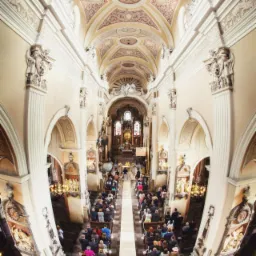 Wnętrze kościoła podczas ceremonii ślubnej, widok z góry z użyciem obiektywu szerokokątnego, ukazujący zdobienia sufitu i tłum gości.