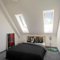 Jasna sypialnia na poddaszu z dwoma oknami dachowymi, czarną narzutą na łóżku i plakatem z czerwoną nogą w rogu